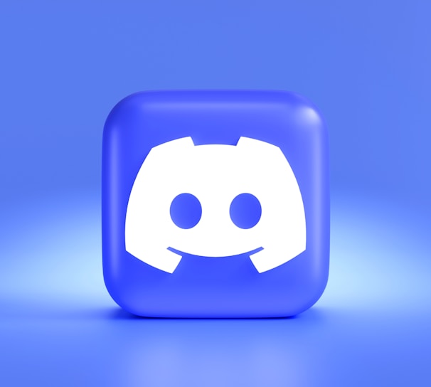 A three-dimensional blue cube featuring a white, stylized gaming controller symbol associated with a popular communication platform, set against a gradient blue background.