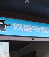 A building entrance features a vibrant blue sign with white Chinese characters and a stylized orca logo in black and white. The overall appearance suggests an establishment focused on eSports or digital activities.